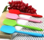 A set of four MOACC multicolor silicone spatulas with rubber and stainless steel handles, arranged neatly on a clean surface.